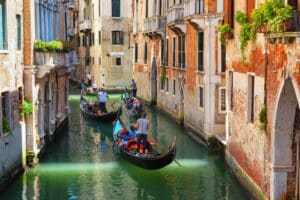 Gondolas sailing tourists along narrow canals