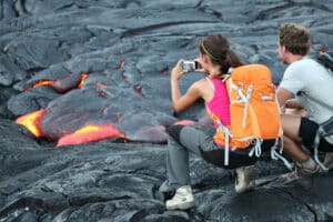 Tourists taking photo of flowing lava from Kilauea volcano around Hawaii volcanoes national park, USA.